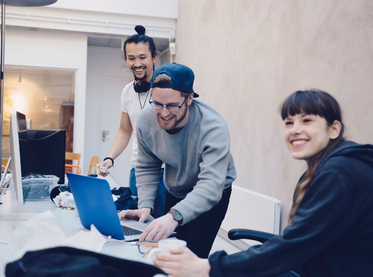 Happy male and female computer programmers at desk in office